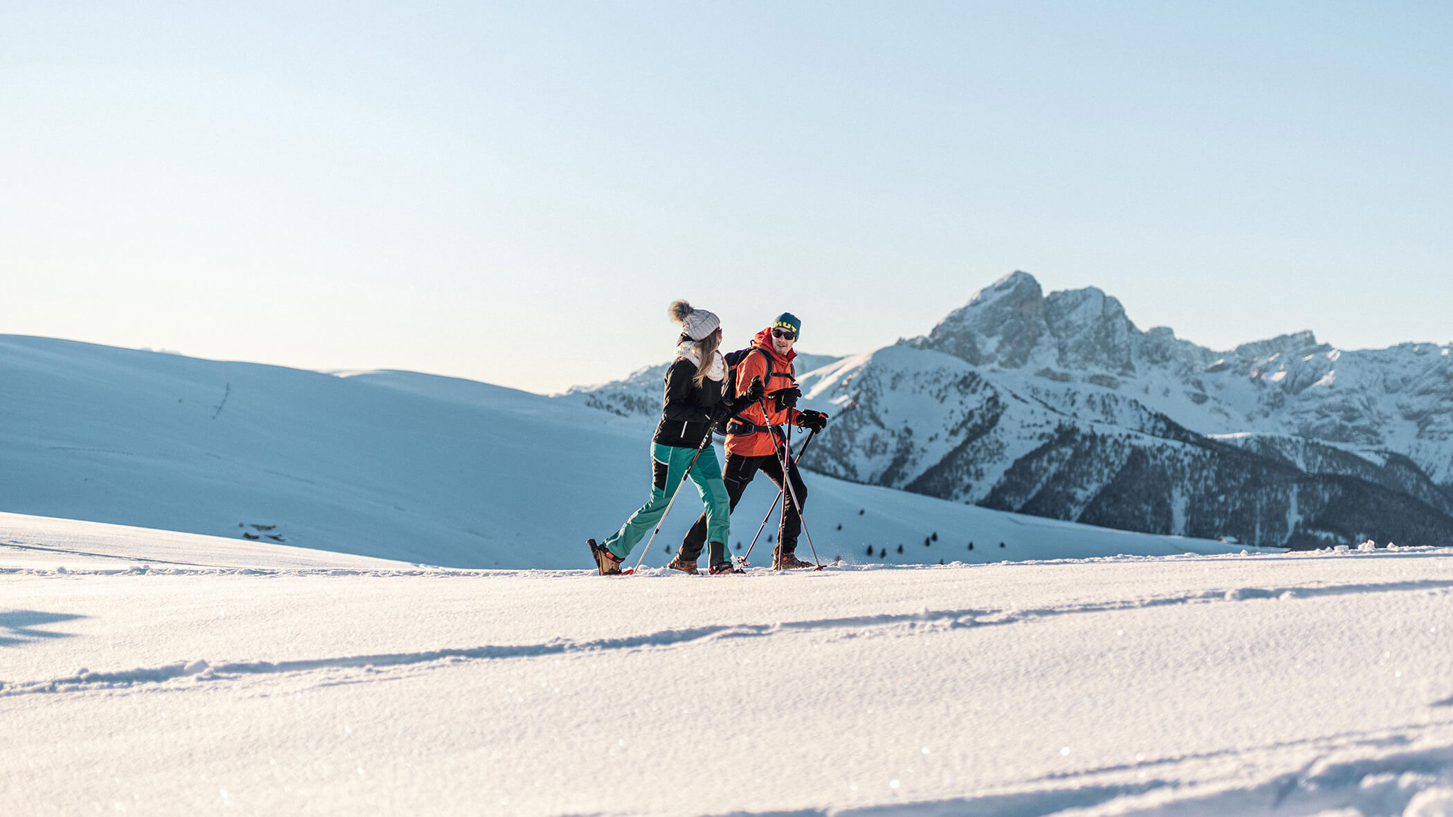 Zwei Schneeschuhwanderer im Neuschnee, im Hintergrund Berge und Wälder - Oberplunerhof