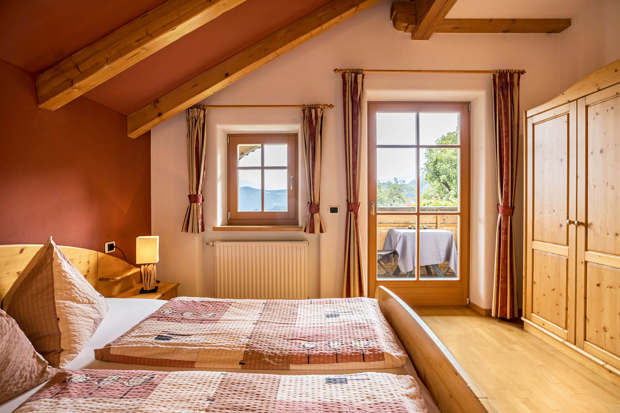 Schlafzimmer im Apartment Bruneck mit Doppelbett, Holzschrank und Blick auf den Balkon - Oberplunerhof