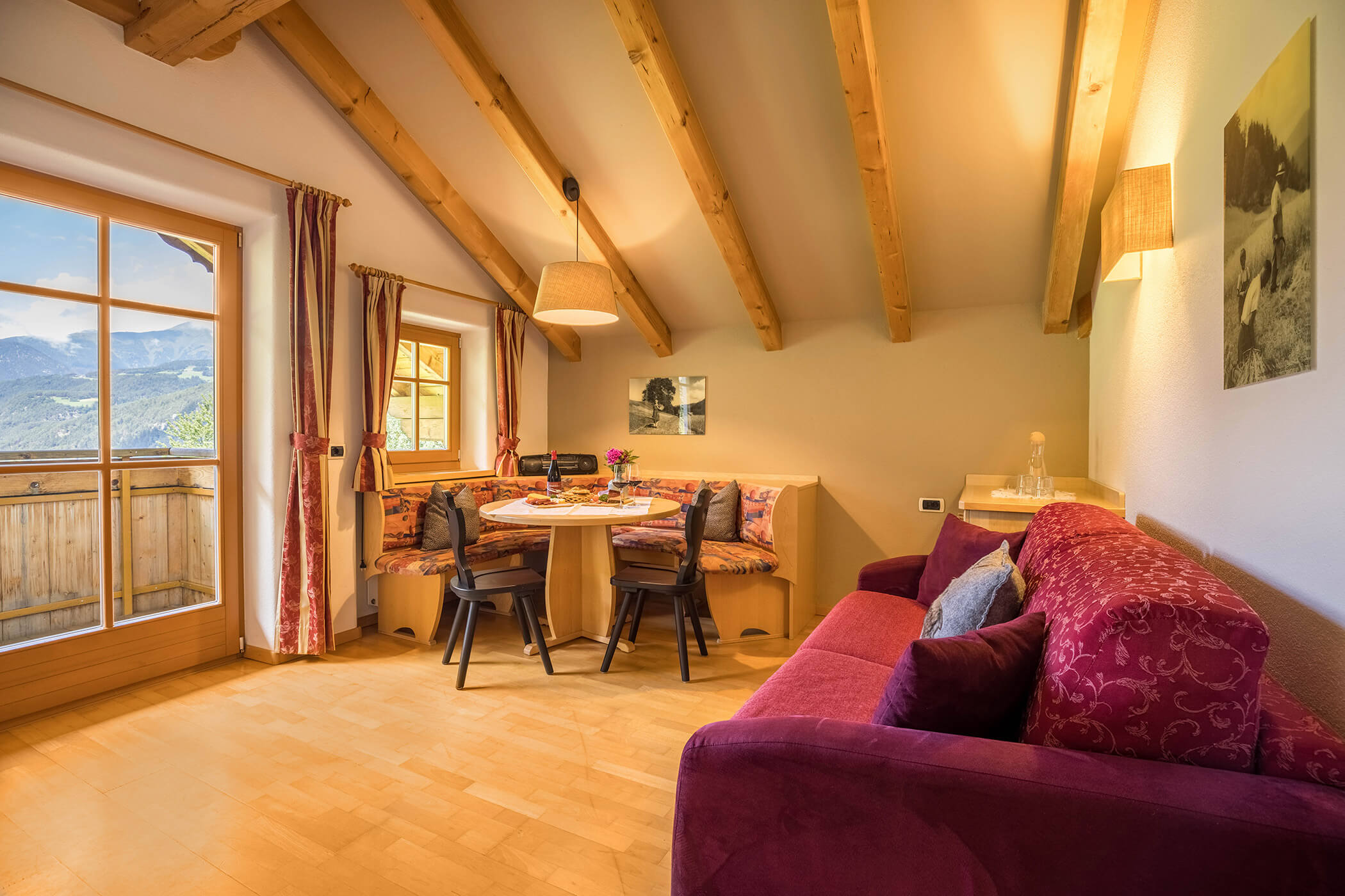 Wohnzimmer mit rotem Sofa, Eckbank und Tisch im Apartment Gitschberg - Oberplunerhof