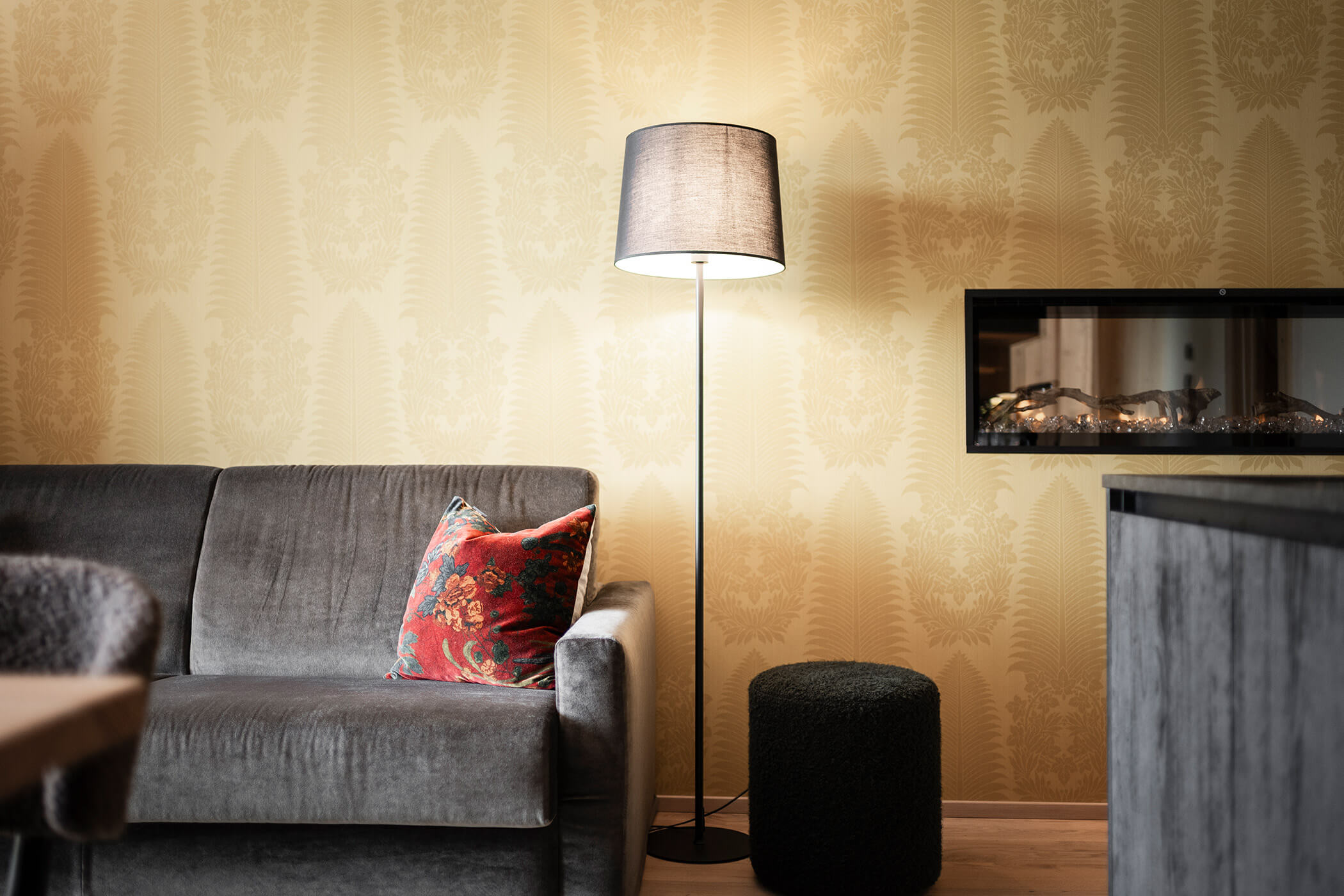 Graues Sofa mit einer Stehlampe und gelber Wand - Oberplunerhof
