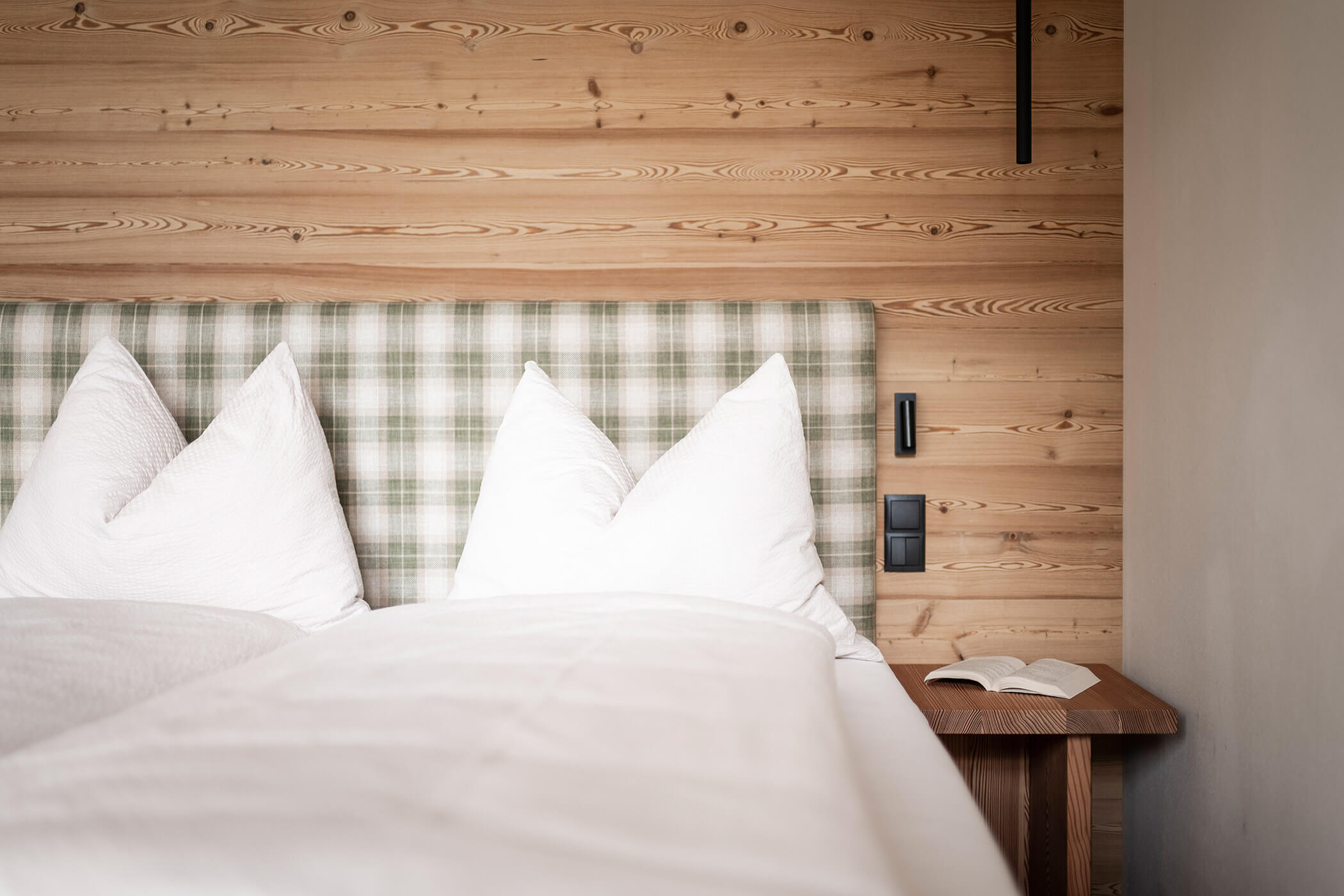Schlafzimmer im Chalet Woods mit Nachttisch und einem Buch - Oberplunerhof