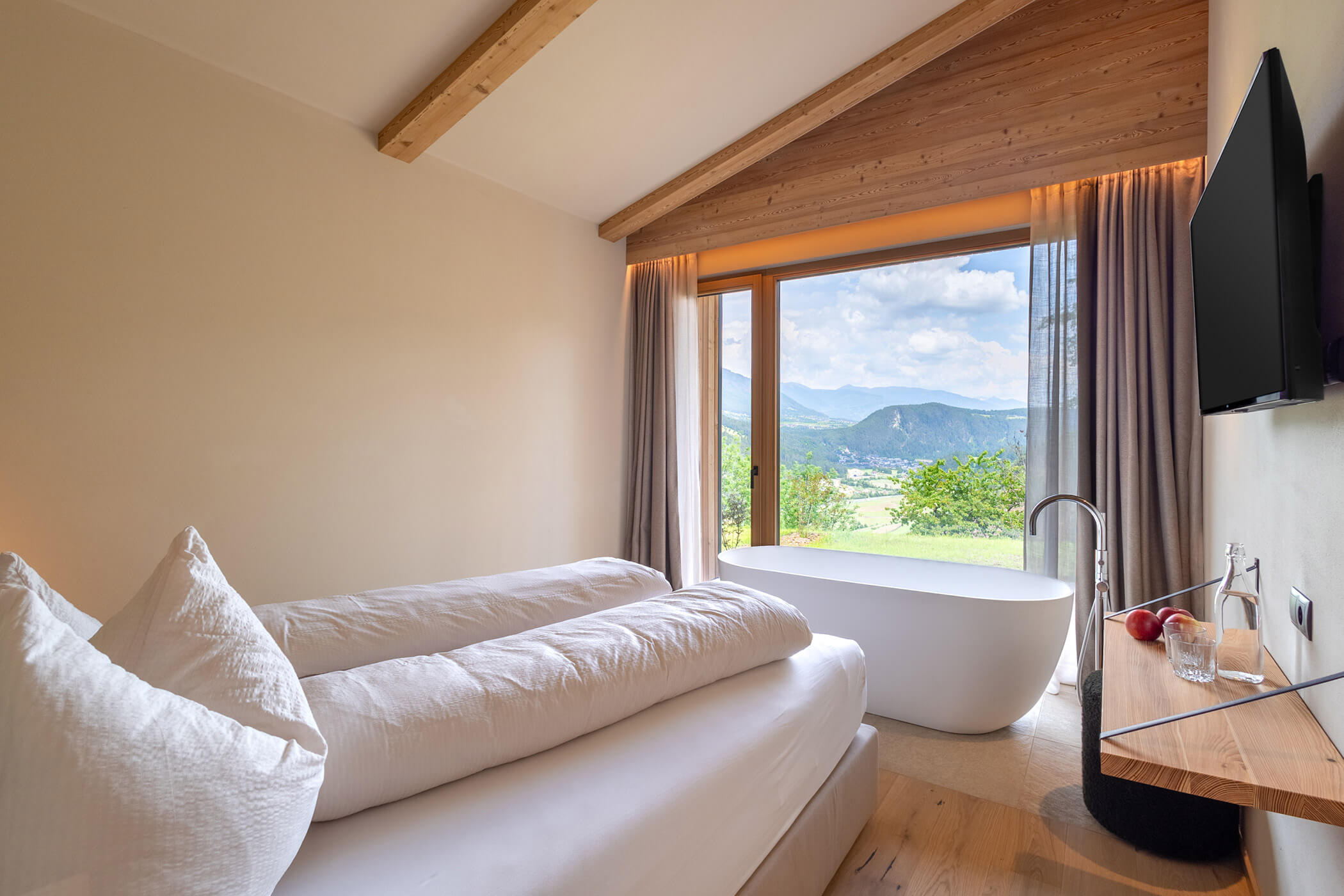 Schlafzimmer im Chalet Woods mit Doppelbett, freistehendes Badewanne und Blick auf das Tal und die Berg - Oberplunerhof