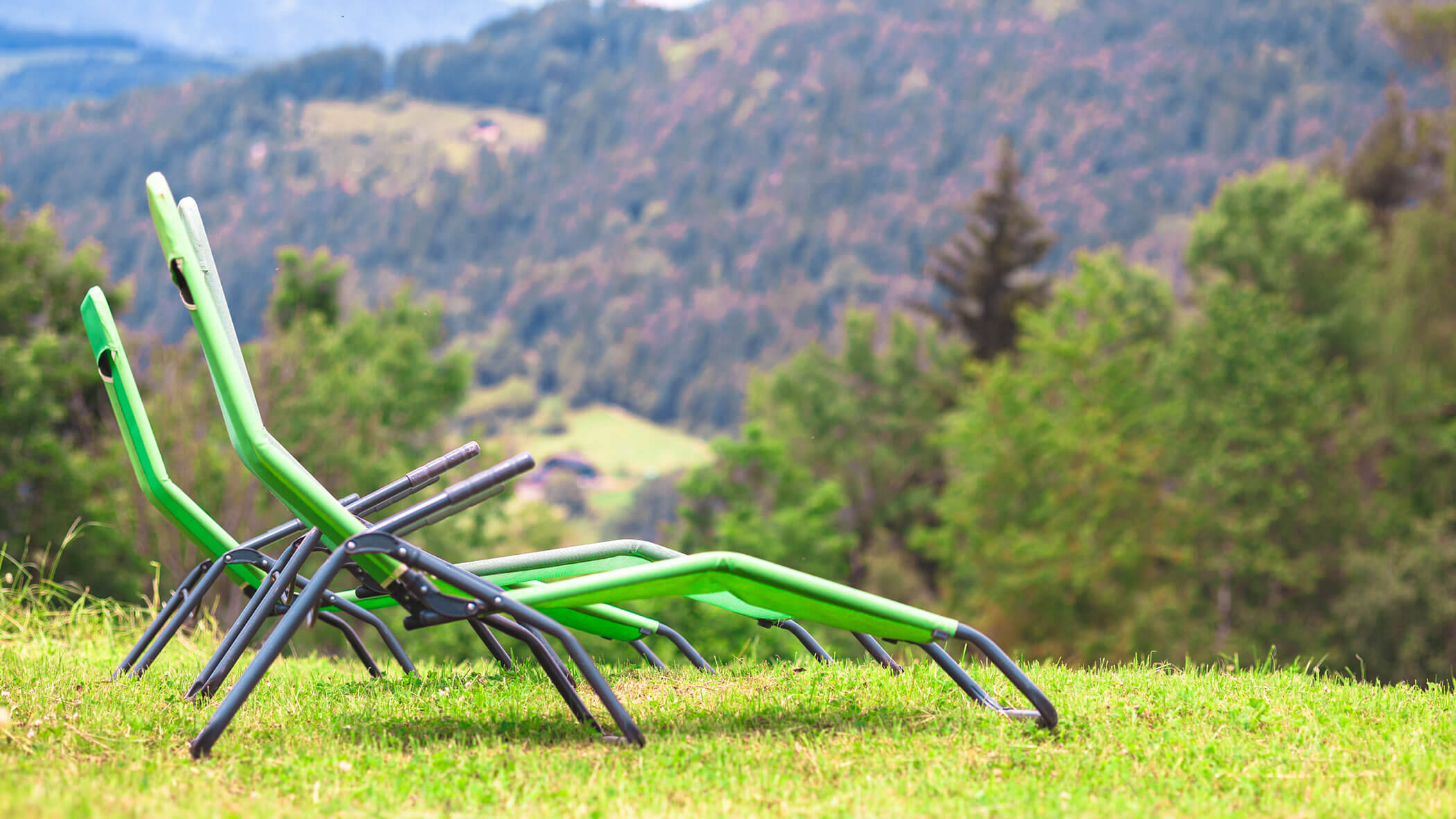 Zwei grüne Liegestühle auf einer Wiese mit Aussicht - Oberplunerhof