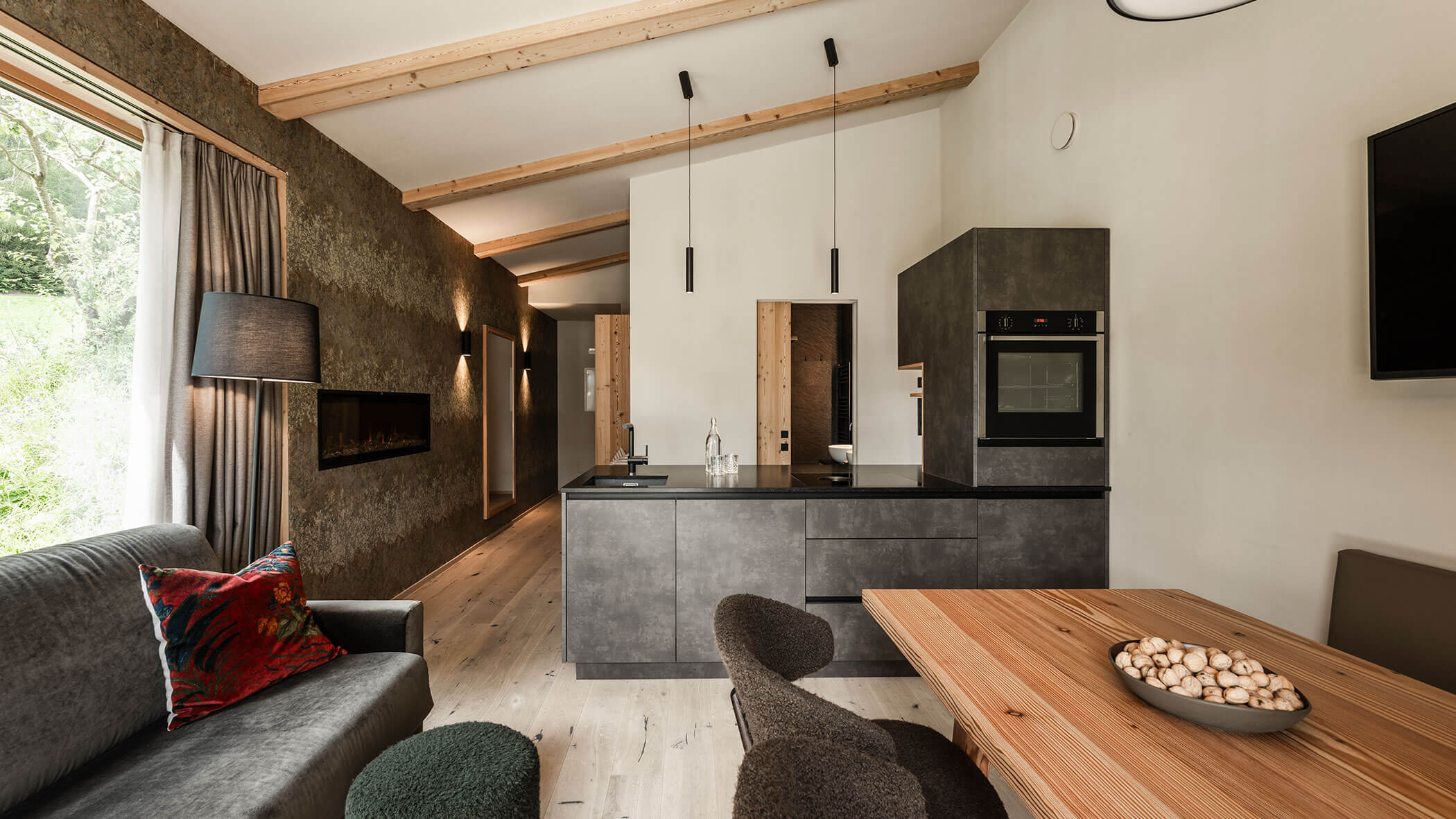 Moderne Wohnküche mit dunkler Küchenzeile, Sofa und hellem Esstisch - Oberplunerhof