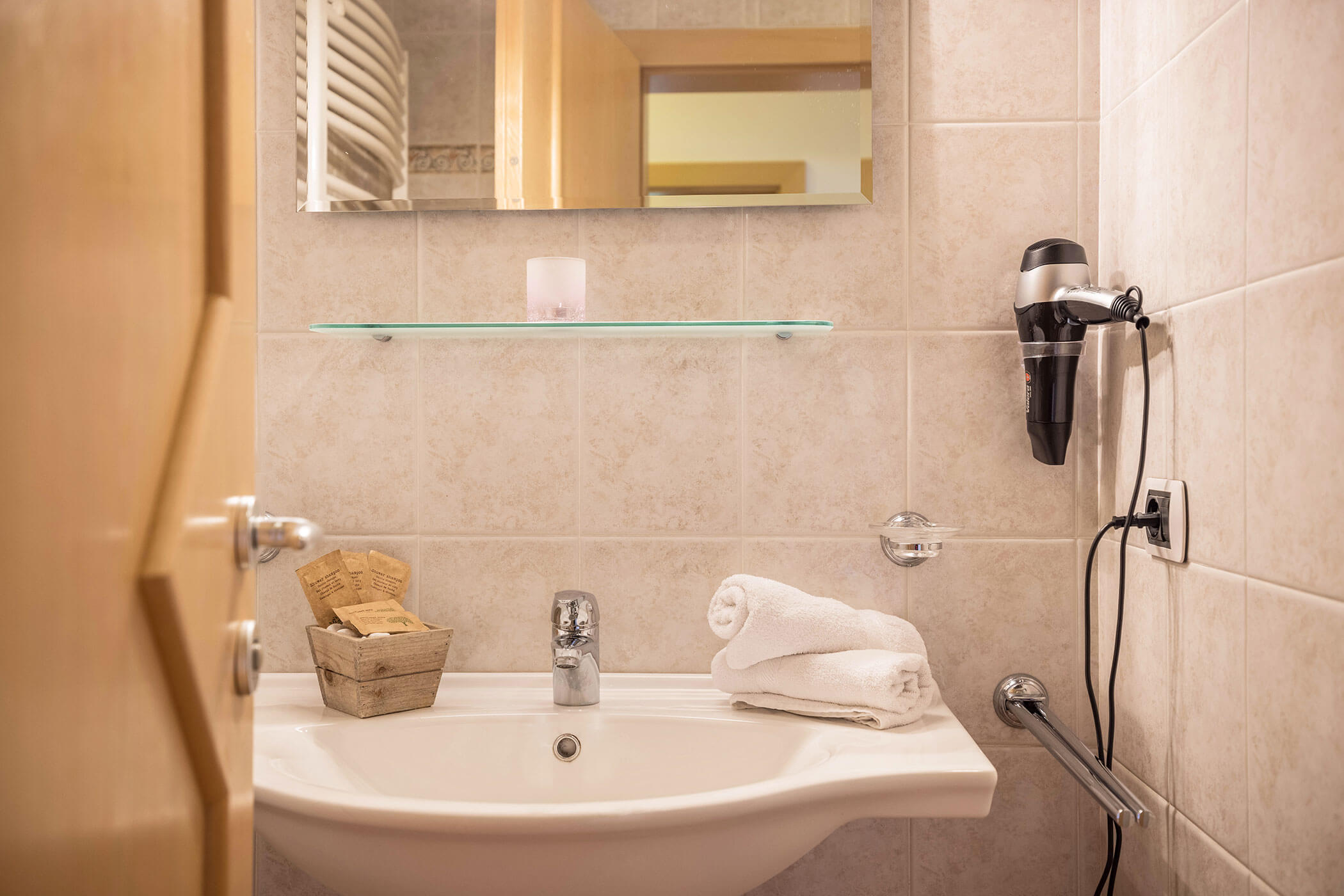 Badezimmer vom Apartment Kronplatz mit Waschbecken, Spiegel und einem Föhn - Oberplunerhof