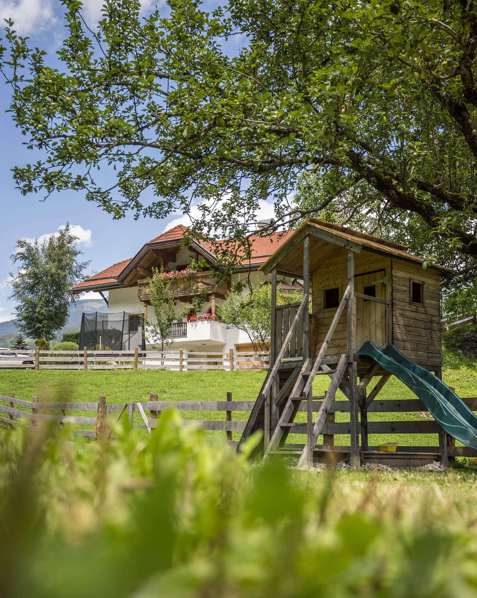 Ein Baumhaus mit Rutsche und im Hintergrund der Oberplunerhof