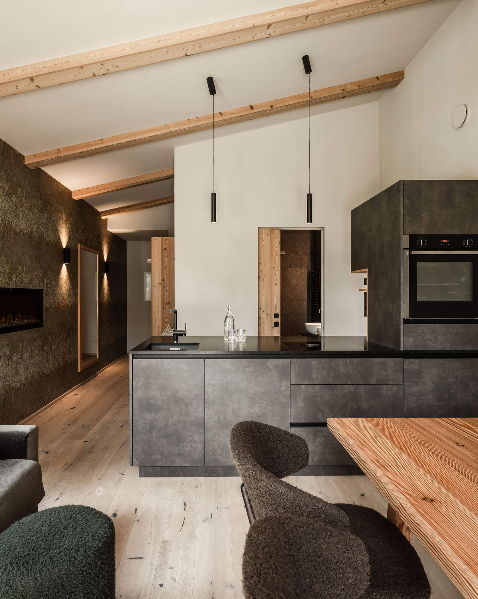 Moderne Wohnküche mit dunkler Küchenzeile, Sofa und hellem Esstisch - Oberplunerhof
