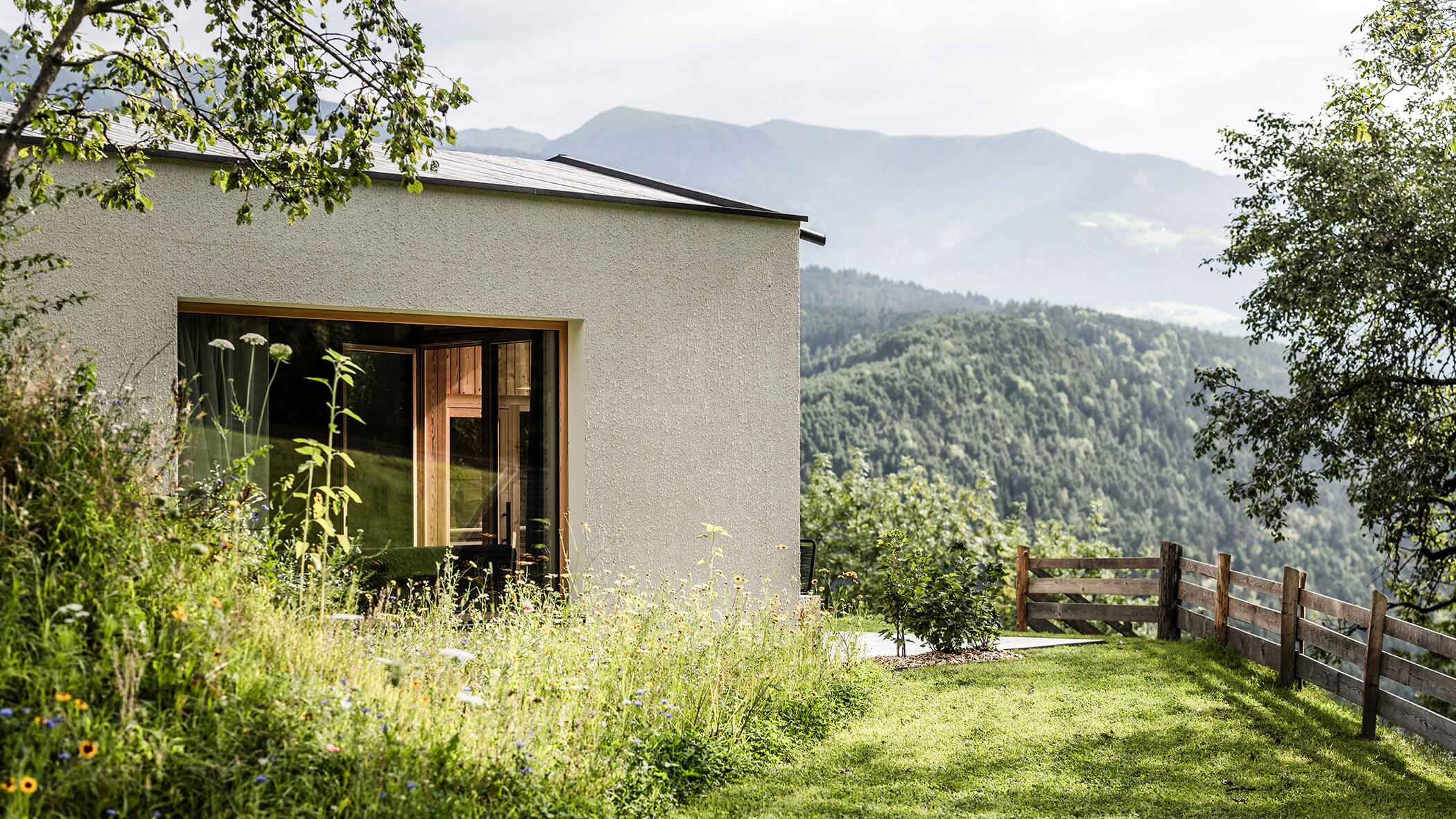Eine grüne Wiese mit Blumen vor dem Chalets - Oberplunerhof