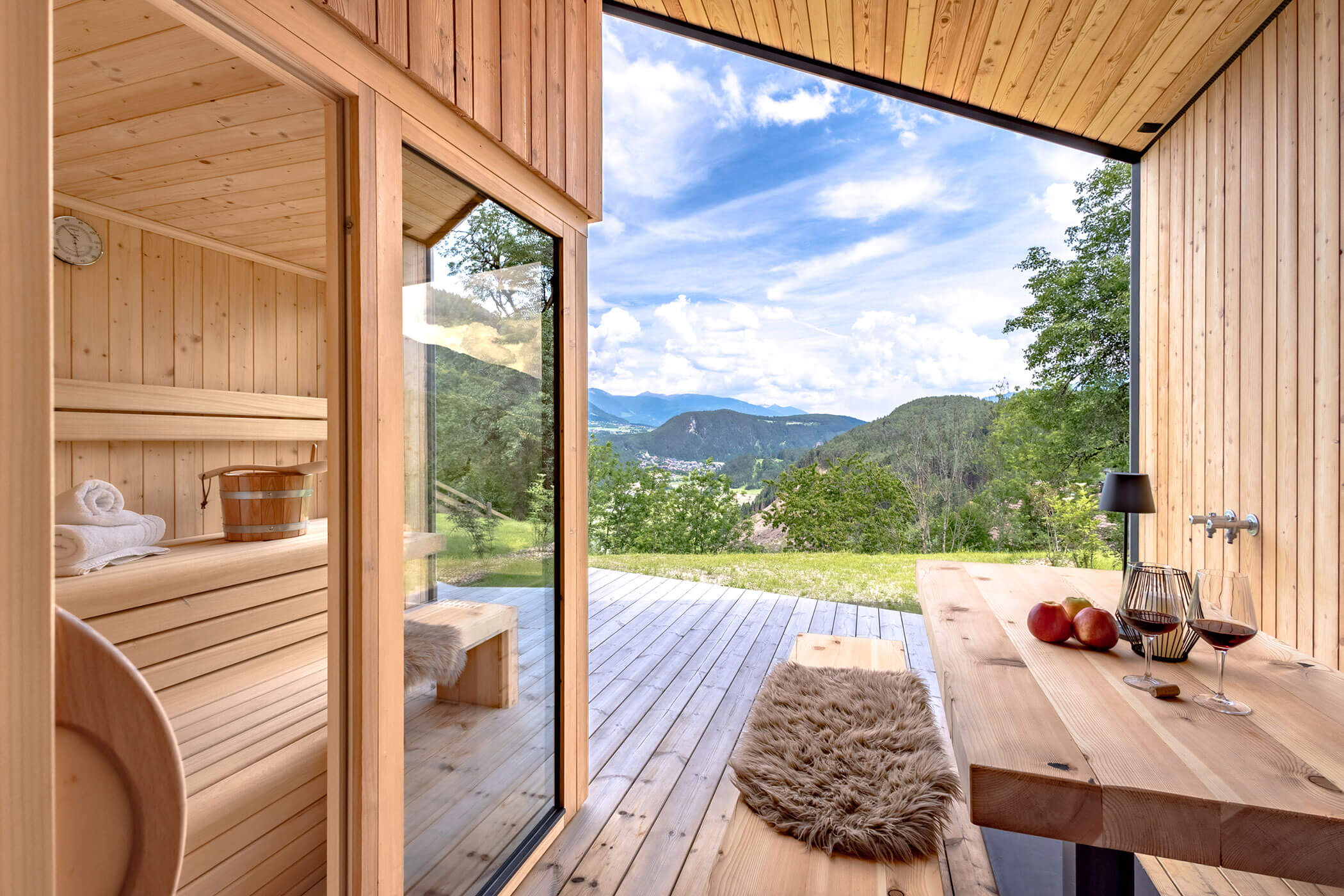 Außensauna mit einer Bank und einem Tisch mit zwei Rotweingläser im Chalet Woods - Oberplunerhof