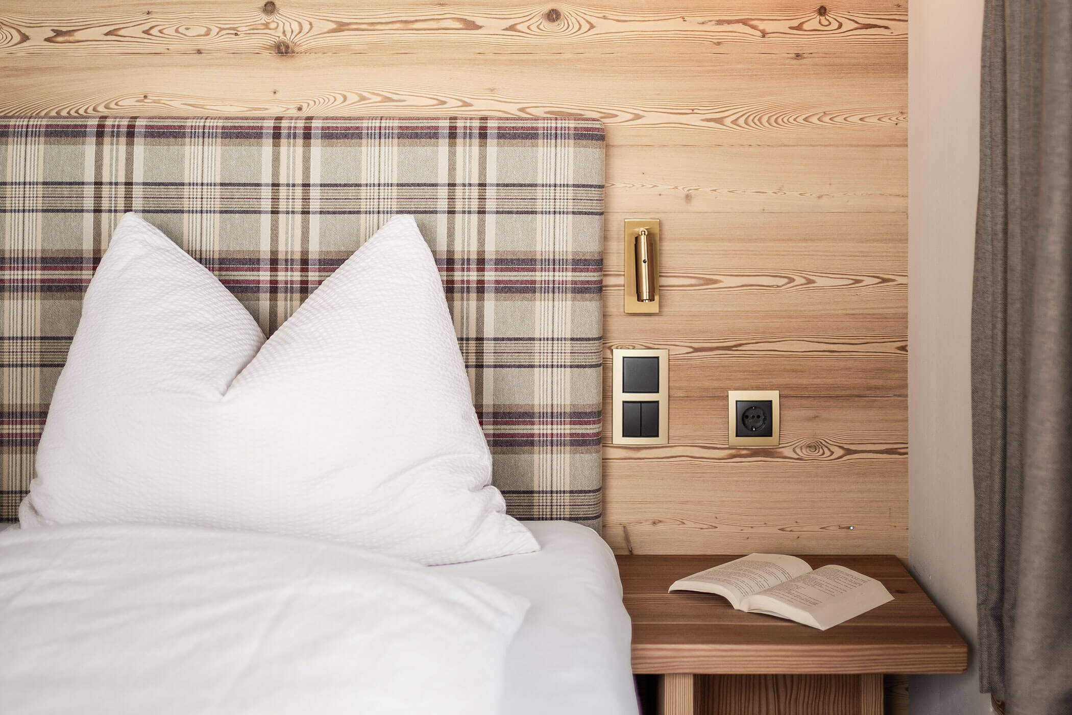 Schlafzimmer im Chalet Skyline mit Nachttisch und einem Buch - Oberplunerhof