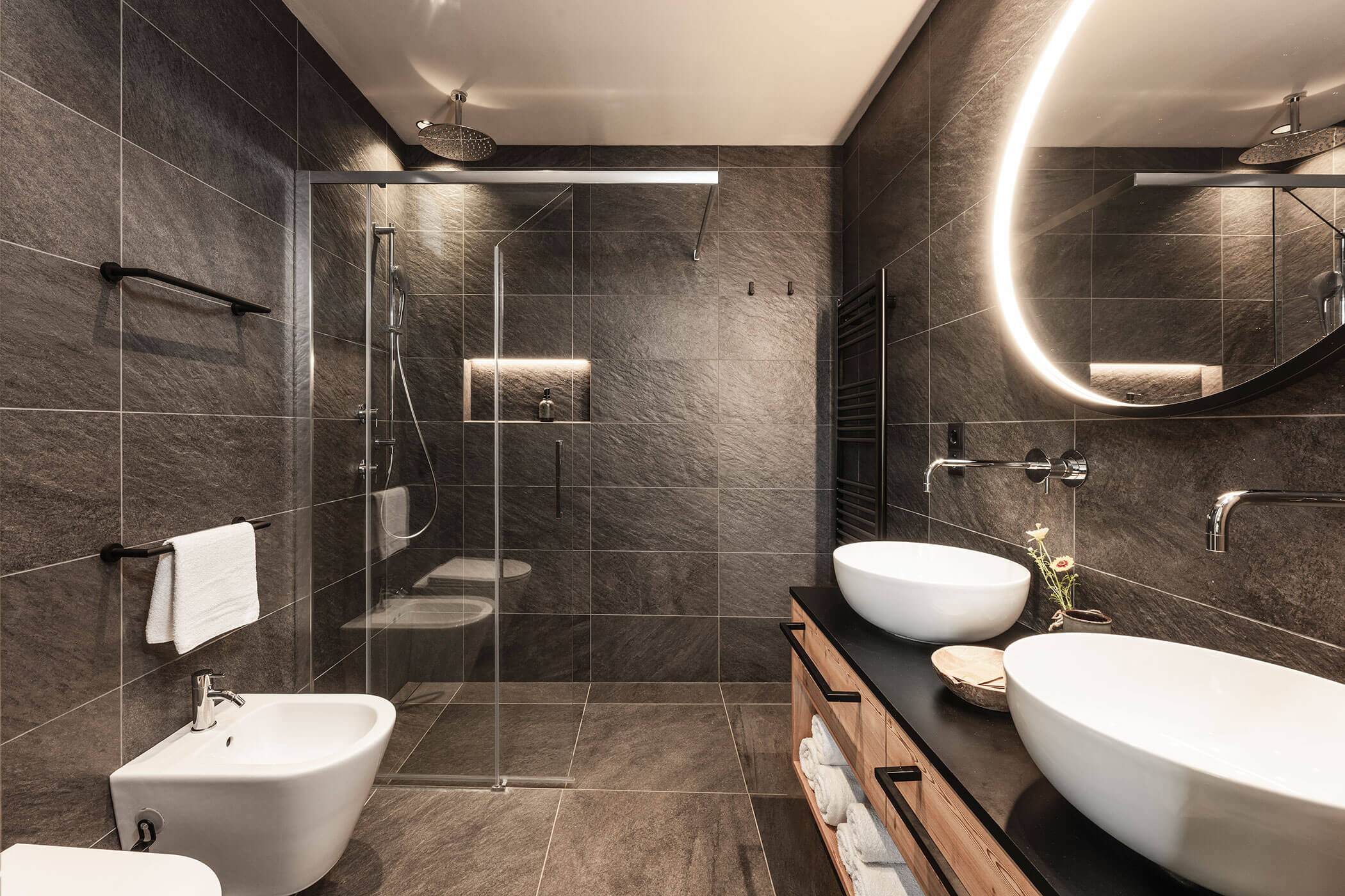 Bad im Chalet Woods mit großem, rundem Spiegel, zwei Waschbecken, Regendusche und WC - Oberplunerhof