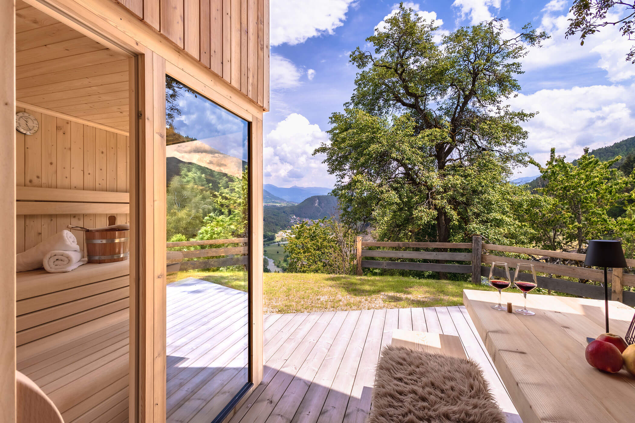 Außensauna mit einer Bank und einem Tisch mit zwei Rotweingläser im Chalet Woods - Oberplunerhof