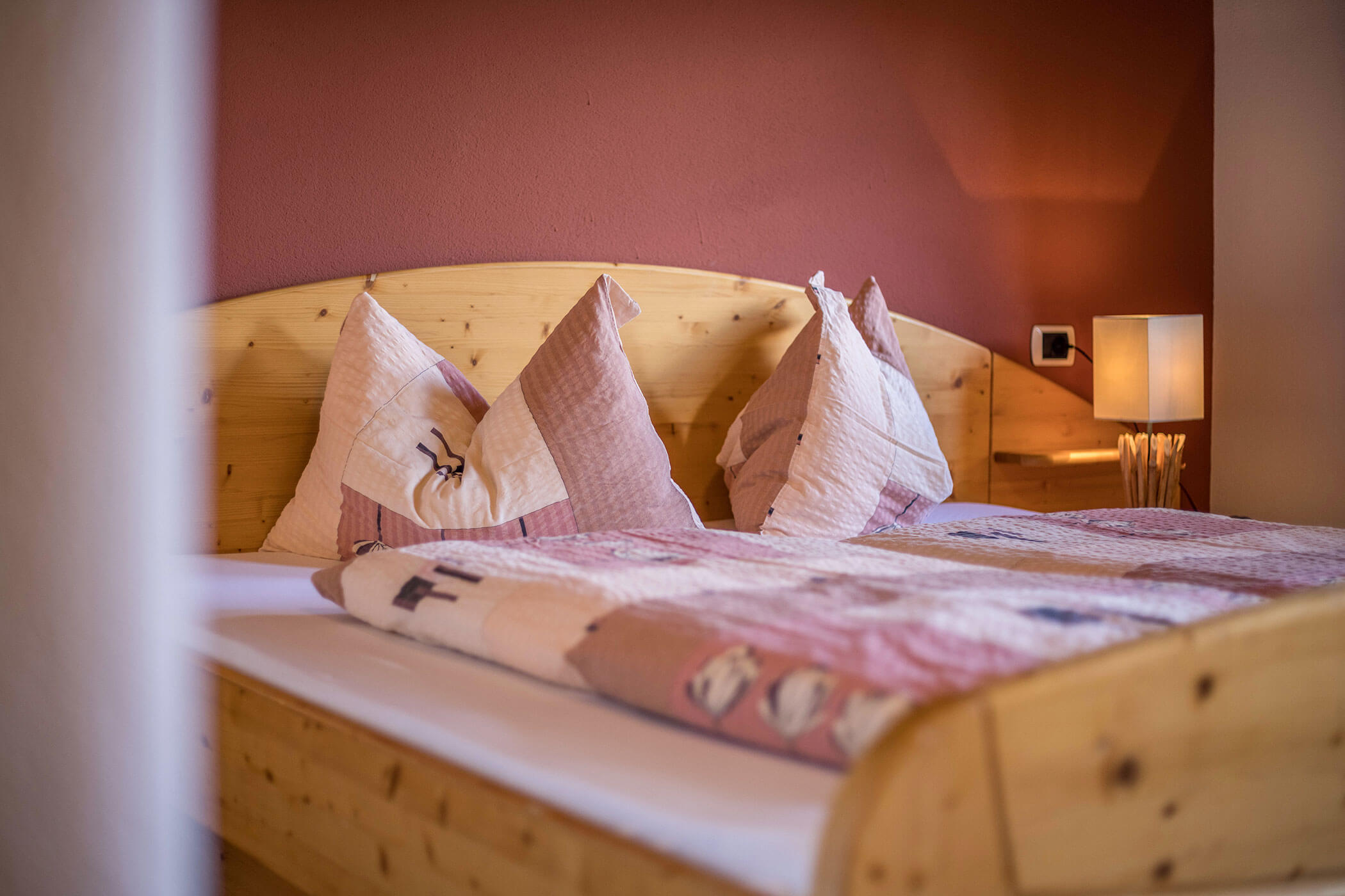 Doppelbett in einer Ferienwohnung des Oberplunerhofs mit gemütlicher Beleuchtung