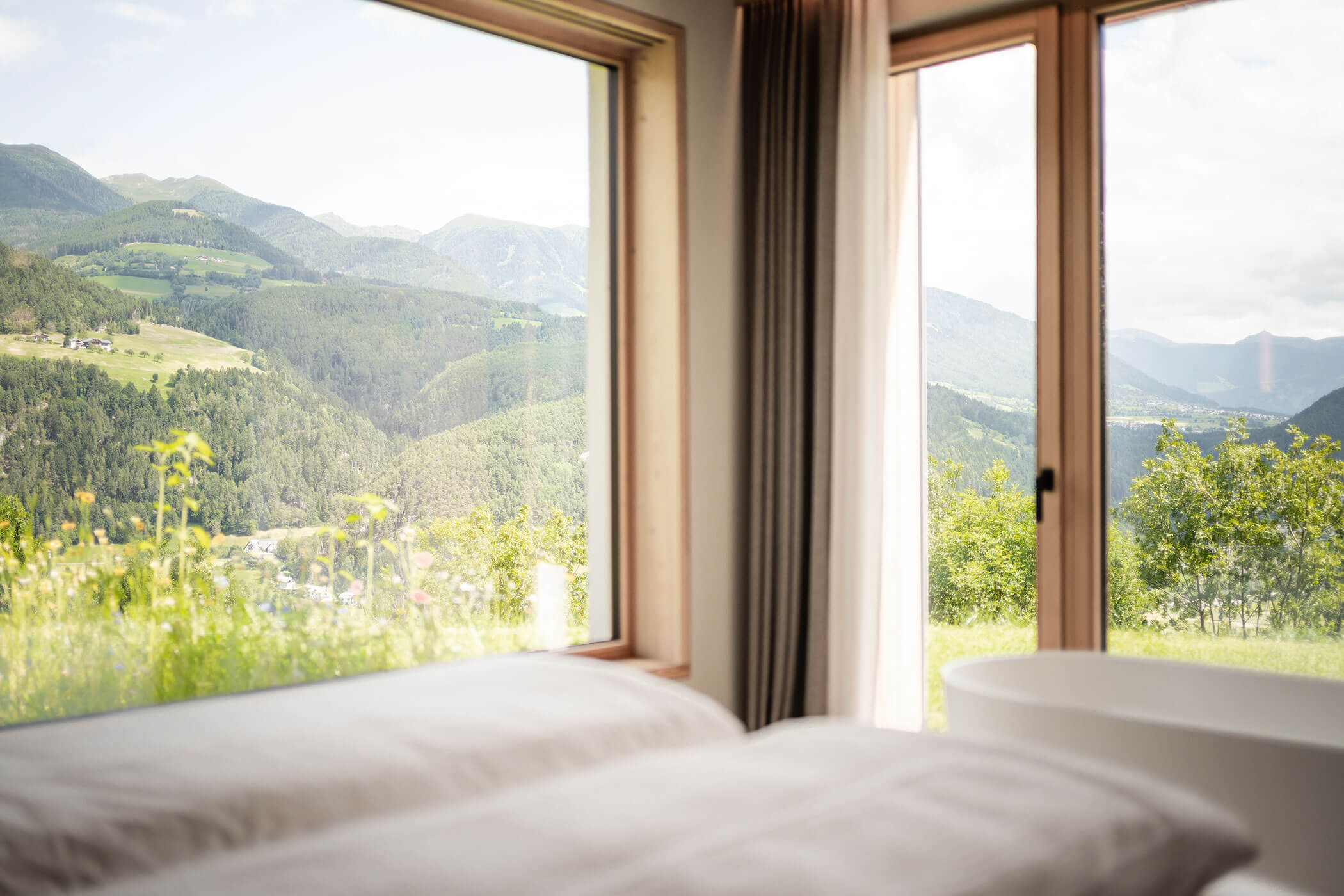 Doppelbett im Chalet Skyline mit freistehender Badewanne davor und Blick in die Natur - Oberplunerhof
